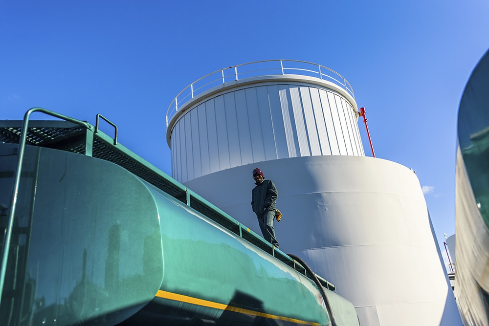Low angle view of worker on top of biofuel oil tanker at biofuel
